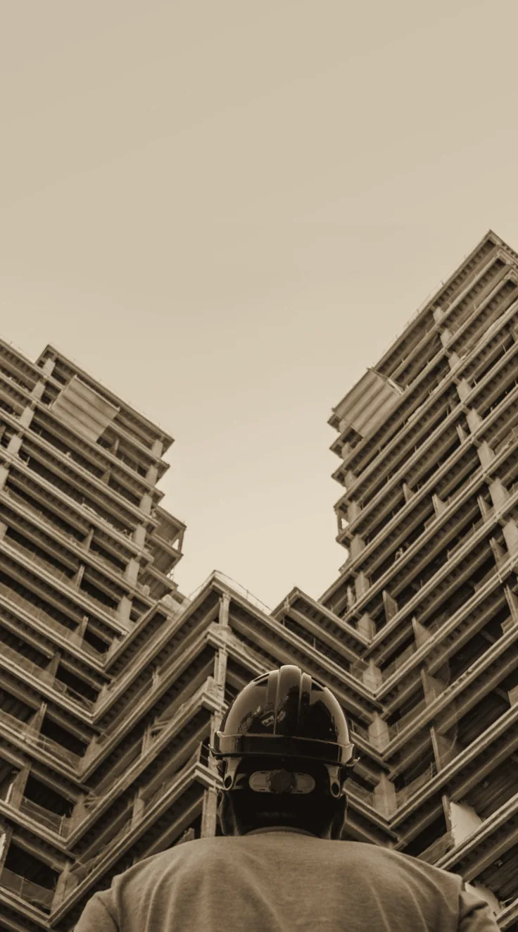 Operário de capacete diante de duas torres em construção — a vertical de Construction da Match Point.